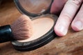 Makeup brush and miror in hand closeup