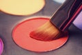 Makeup brush on red shadows. Bright shadows for the summer. Macro frame of shadows. Bright cosmetics, fashionable colors. Royalty Free Stock Photo