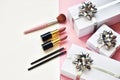 Makeup brush set and lipsticks, gifts boxes on a pink-white background.