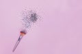 Makeup brush and strar shapped small confetti on pastel pink background.