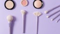 Makeup brushes for blush, highlighter and powder on purple background. Applying of makeup brushes. Cosmetic, professional brushes