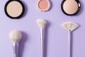 Makeup brushes for blush, highlighter and powder on purple background. Applying of makeup brushes. Cosmetic, professional brushes