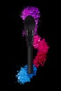 Makeup brushes and colorful eyeshadows on a black background, top view, colorful crushed eyeshadow powder