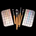 Makeup brushes and colorful make-up eye shadows palette on black background. Fashion woman still life. Royalty Free Stock Photo