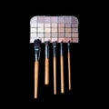Makeup brushes and colorful make-up eye shadows palette on black background. Fashion woman still life. Royalty Free Stock Photo