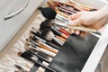 Makeup brushes are in a drawer at the makeup artist& x27;s workplace. A woman& x27;s hand holds makeup brushes. close-up Royalty Free Stock Photo