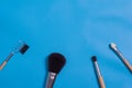 Makeup brushes, everyday make-up tools. Cosmetic essentials on blue background, closeup