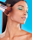 Makeup, brushes and Indian woman with foundation, facial treatment and girl against a blue studio background. Female