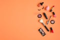 Makeup cosmetics and beauty products spilling out on pastel peach colored background. Flat lay, top view. Beauty salon banner