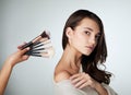 Makeup, face brush and beauty of a woman in studio with natural glow on skin. Portrait of female person on a grey Royalty Free Stock Photo