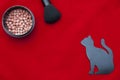 Makeup flat lay on the red background. Face powder, makeup brush and stencil in the form of a cat for drawing eye lines.