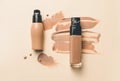 Bottles of makeup foundation and samples on color background Royalty Free Stock Photo