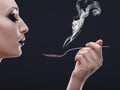 Makeup, hot and woman blowing a spoon with steam in studio with gothic, cool and danger aesthetic. Mockup, art and