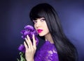 Makeup. Long hair. Beautiful brunette woman with purple flowers, manicured nails, healthy black hairstyle. Beauty studio portrait.