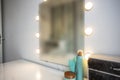 Makeup mirror on table near white wall in dressing room Royalty Free Stock Photo