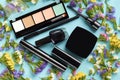 Makeup objects with colored flowers on blue background composition Royalty Free Stock Photo
