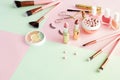 Makeup products, decorative cosmetics on pastel color pink mint background flat lay.