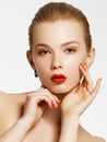 Makeup products. Young beautiful girl with gold earrings and ring smiling on white background. Red nails with manicure