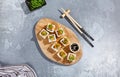 Maki roll with fried carrot and green onion top on wooden board in contemporary composition. Sushi roll with chopsticks on