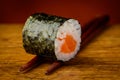 Maki sushi roll on chopsticks Royalty Free Stock Photo