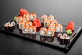 Maki Sushi set on dark pattern background. Sushi Set nigiri, rolls and sashimi served in black square plate Royalty Free Stock Photo