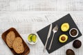 Making avocado toast for breakfast. Slices of fresh rye bread, avocado and lime on the black plate on the white wooden table. Royalty Free Stock Photo