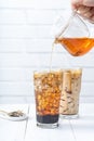 Making bubble tea, pouring blend milk tea into brown sugar pattern drinking glass cup