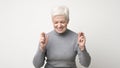 Optimistic senior woman crossing fingers with hope with closed eyes Royalty Free Stock Photo
