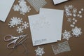 Making Christmas Greeting Card with Snowflakes. Handmade decorating with Paper Snowflakes with Beads on Brown Background Royalty Free Stock Photo