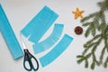 Making a Christmas tree out of paper. Scissors, blue paper, and fir branches on a light table. An original children`s art project Royalty Free Stock Photo