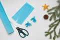 Making a Christmas tree out of paper. Scissors, blue paper, and fir branches on a light table. An original children`s art project Royalty Free Stock Photo