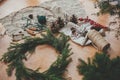 Making Christmas wreath. Fir branches, pine cones, thread, berries, cinnamon on wooden table. Rustic Christmas wreath workshop.