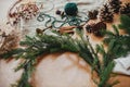 Making Christmas wreath. Fir branches, pine cones, thread, berries, cinnamon on wooden table. Rustic Christmas wreath workshop.