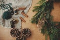 Making Christmas wreath flat lay. Fir branches, pine cones, thread, cinnamon on wooden table. Rustic Christmas wreath workshop.