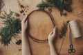 Making christmas wreath flat lay. Hands holding wooden circle and fir branches, pine cones, thread, scissors, herbs on wooden Royalty Free Stock Photo