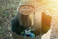 Making coffee process on campfire. Close up coffe in turk cezve on Camping Stove Mini Outdoor Stoves Gas Burner Royalty Free Stock Photo