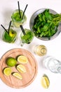 Making a cold summer mojito drink with lime, mint leaves, straw, ice cubes, soda and rum on a white background Royalty Free Stock Photo