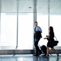 Making conversation on the way to departures. two businesspeople talking together while walking through an airport. Royalty Free Stock Photo