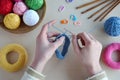 Making crochet pyramid from colored rings. Toy for babies and toddlers to learn mechanical skills and colors. On the table threads Royalty Free Stock Photo