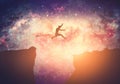 Making a dream come true. Man jumping between mountains on galaxy night sky