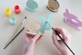 Making Easter decoration - easter eggs and bunny. Painting and coloring wooden toy of brushes and gouache. Creative process.