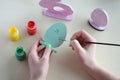 Making Easter decoration - easter eggs and bunny. Painting and coloring wooden toy of brushes and gouache. Creative process.