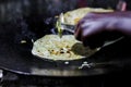 Making of egg roll on a hot frying pan with oil and paratha and salad