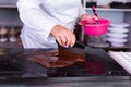 Professional chef holding pink bowl while making chocolate glaze