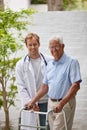 Making great progress with the help of his doctor. Portrait of a male doctor standing with his senior patient whos using