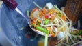 Making of green papaya salad with ingredients crab dried shrimp are mixing and pounding in a mortar.