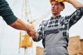Making handshake. Two construction workers in uniform and safety equipment have job on building together Royalty Free Stock Photo