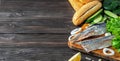 Making herring fillet sandwich with onions, cucumber and salad on a wooden board. Dark wooden background with copy space for text