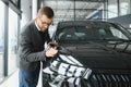 Making his choice. Horizontal portrait of a young man in a suit looking at the car and thinking if he should buy it Royalty Free Stock Photo