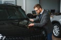 Making his choice. Horizontal portrait of a young man in a suit looking at the car and thinking if he should buy it Royalty Free Stock Photo